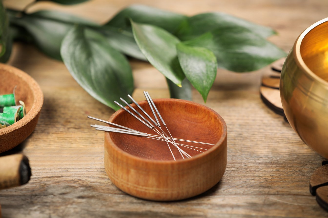 Bowl with Acupuncture Needles on Wooden Table